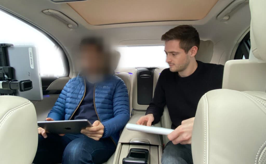 In-car user study: a participant operating the companion app on a tablet in the rear seat while the researcher observes